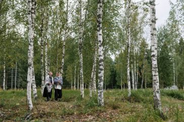 Two women walking in a peaceful birch forest, enjoying the tranquility of nature.