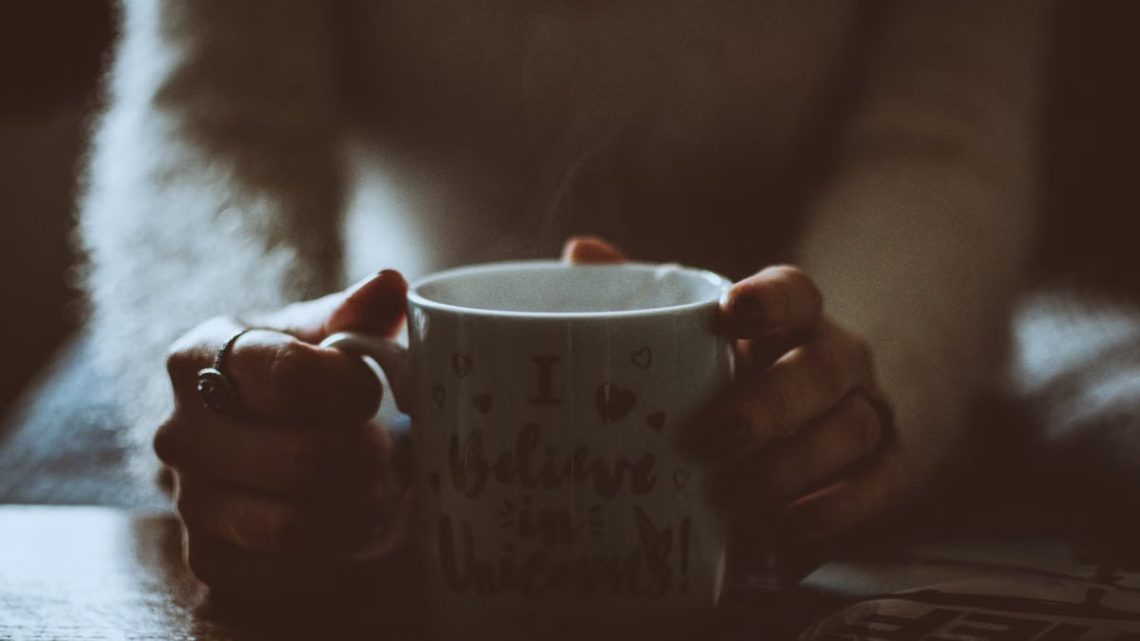 A person holding a warm coffee mug with a whimsical message indoors, creating a cozy ambiance.