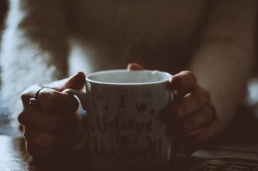 A person holding a warm coffee mug with a whimsical message indoors, creating a cozy ambiance.