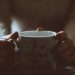 A person holding a warm coffee mug with a whimsical message indoors, creating a cozy ambiance.